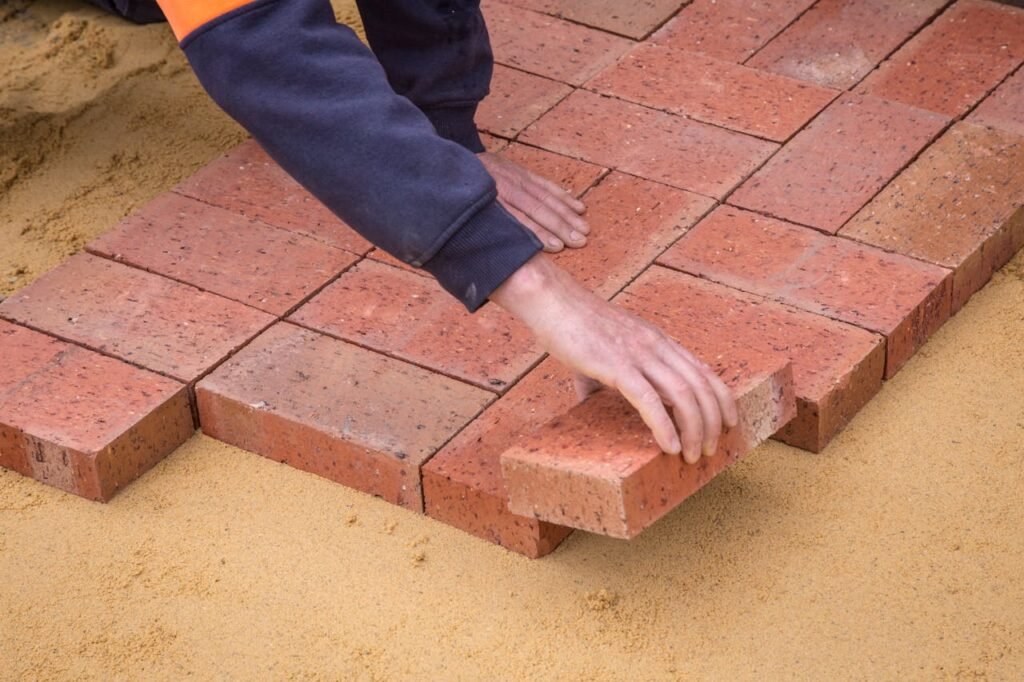 Crop faceless man laying bricks on ground